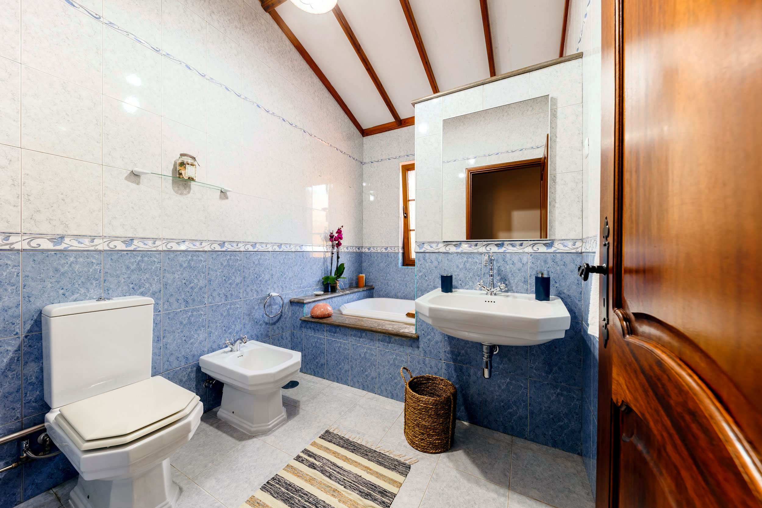 Bathroom with toilet, bathtub, bidet and an orchid at Refúgio Azores stay in Terceira.